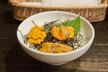 Premium supreme delicious fresh from the sea 3 types of uni sea urchin sashimi on top of warm steamed rice with crispy grilled seaweed.