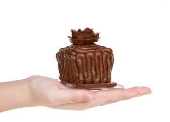 Hand holding one chocolate cake cupcakes on a chocolate candy bar frosted with choc frosting, handmade chocolate  rose on top, sitting on square clear plates isolated on white background
