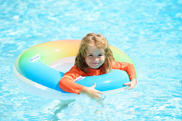 Happy kid playing with colorful swim ring in swimming pool on summer day. Child water toys. Children play in tropical resort. Family beach vacation.