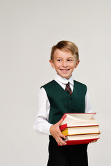 Portrait handsome preteen schoolboy in uniform in front of white background. Cute guy holding a stack of books. Day of Knowledge - September 1. World Read Aloud Day