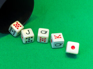 A royal flush by poker dice on the green table.