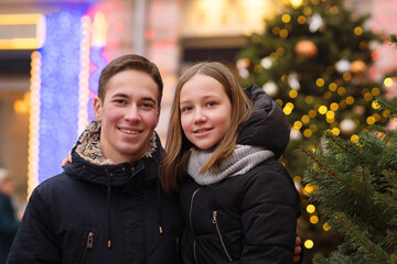 Brother and sister are walking on Christmas Eve in the city streets. Merry Christmas and Happy Holidays. Family for a walk