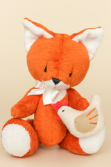 Soft toy ginger fox with chicken on a light background.