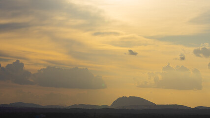 Silhouette of hills against beautiful golden hour light with wide angle and beautiful clouds formation and a glimpse of blue sky