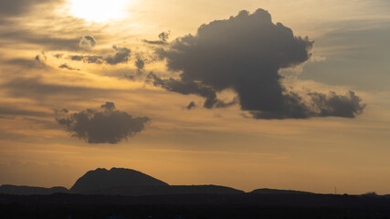 Silhouette of hills against beautiful golden hour light with wide angle and beautiful clouds formation and a glimpse of blue sky