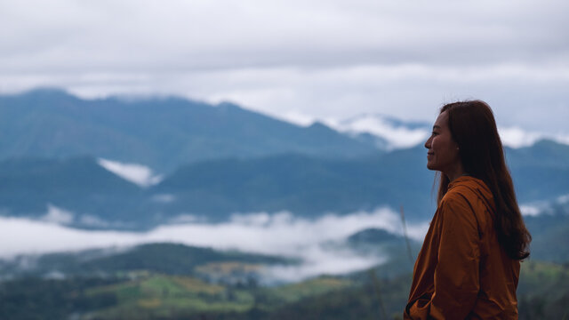 Portrait image of a female traveler looking at a beautiful foggy mountain and nature view