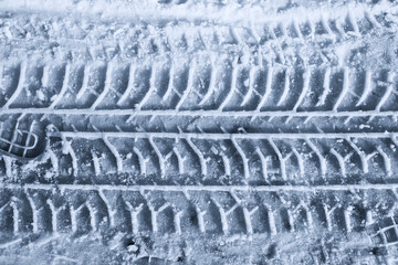 Trace of Protector car tires in the melted snow. Top view in blue toning. Close-up.