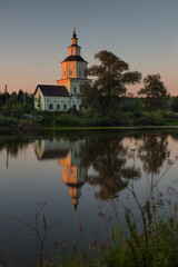 Fototapeta na wymiar Village church with pond at sunset with reflection