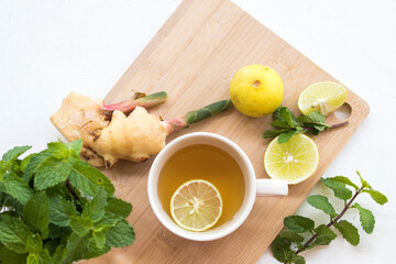 herbal healthy drinks hot tea honey lemon for health care with peppermint leaf and lemon slice for relaxation on background white wooden