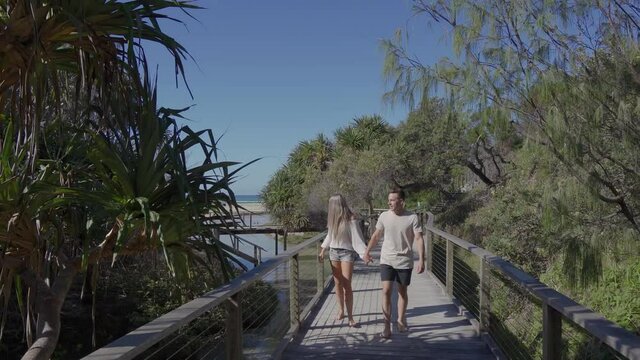 Young Couple Walking on nature boardwalk at Eli Creek, Fraser Island - wide shot tracking backwards