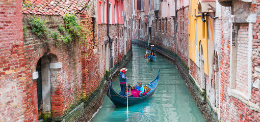 Naklejka na ściany i meble Venetian gondolier punting gondola through green canal waters of Venice Italy