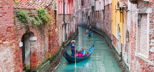 Acrylic prints Gondolas Venetian gondolier punting gondola through green canal waters of Venice Italy