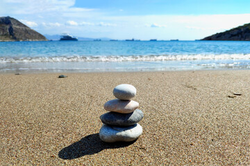 Fototapeta na wymiar Pyramid of sea stones on the seashore at the pebble beach. Concept of harmony and balance. Selective focus.