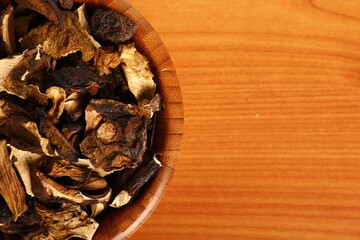 Dried mushrooms in wooden bowl. Boletus badius.