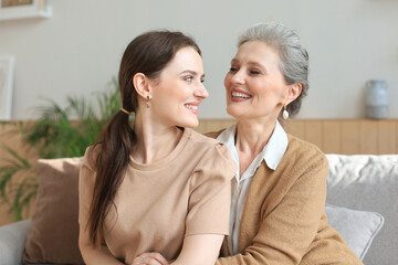 Beautiful mother and daughter. Cheerful young woman is embracing her middle aged mother in living...