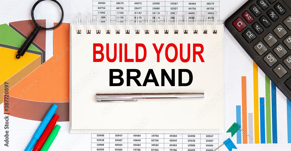 Poster build your brand text on the notepad on chart background with pen and glasses