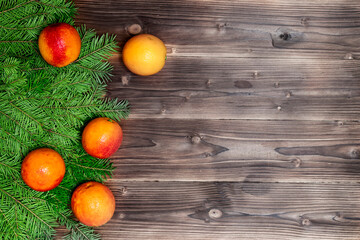 Orange tangerines or mandarines and fir branches on wooden background. Mandarine tangerine winter concept