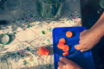 5. Step by step pickling of tomatoes for the winter in the village. A woman cuts a carrot into circles for pickling a tomato.