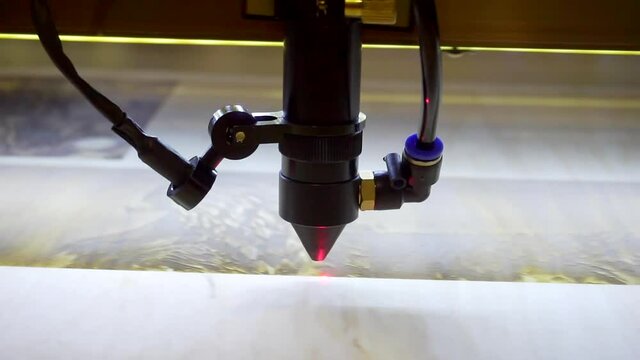 3D printer laser beam burns the pattern close-up on a wooden board.