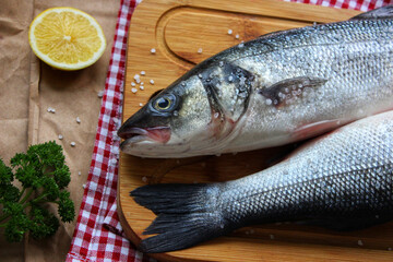 Raw fish on a cutting Board decorated with a slice of lemon close up