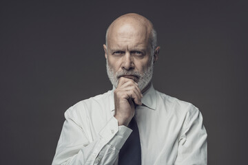 Obraz premium Confident businessman thinking with hand on chin