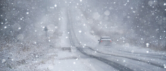 The car is driving on a winter road in a blizzard	
