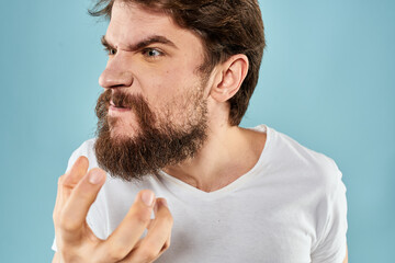 Obraz premium Bearded man in white T-shirt emotions gestures with hands displeased facial expression blue background