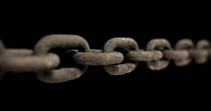 Slow panning across an old rusty chain showing each link pulled taut. Concept of strength, security, or strong connection.
