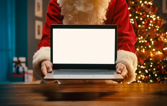 Santa Claus holding a laptop with blank screen