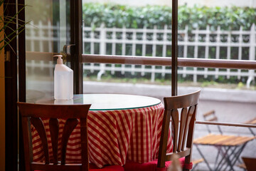 front view of disinfectant bottle standing on wooden table inside cafe