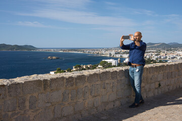 Fototapeta na wymiar man taking pictures of a beautiful bay in the mediterranean sea