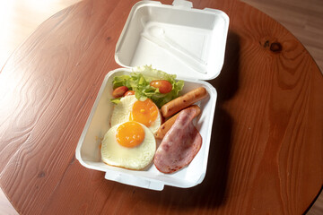 American breakfast meal style in a paper box set. Small meal of hams and fried eggs.