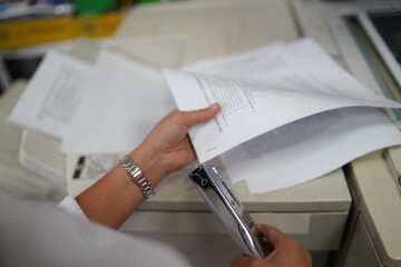 Woman hands holding papers and stapling documents in office