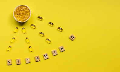 Yellow capsules in the form of the sun with rays and word vitamin D from wooden cubes with letters