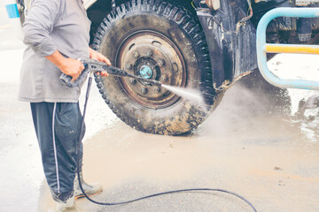 Worker or labor using a high pressure water jet washer to wash and point to the front wheel truck...