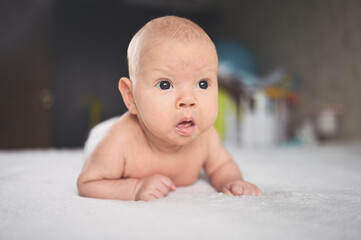 Cute emotional funny newborn infant boy laying on bed. Baby facial expressions.