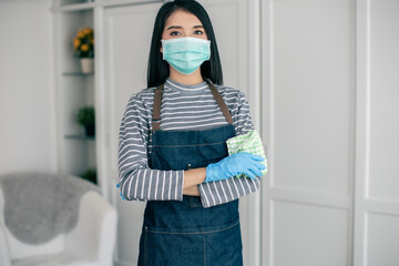 Fototapeta na wymiar Asian Woman professional cleaner in protective medical mask cleaning desk at home.Home, housekeeping concept .She wear mask protect covid-19.