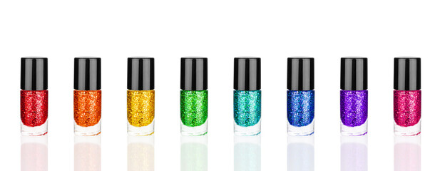 Obraz premium Colorful glittering nail polish glass bottles set white background isolated close up, sequin varnish closed containers collection, rainbow sparkling enamel, shiny lacquer, shimmer gel, beauty cosmetic