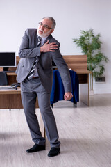 Old male employee suffering from radiculitis at workplace