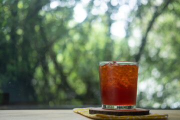 Homemade iced tea in small glass on wood table.
