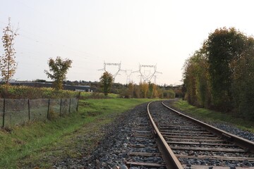 Fototapeta premium Voie de chemin de fer unique avec traverses en bois de type vignole, au milieu de la campagne en automne, ville de Saint Quentin Fallavier, département de l'Isère, France