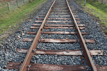 Obraz premium Voie de chemin de fer unique avec traverses en bois de type vignole, au milieu de la campagne en automne, ville de Saint Quentin Fallavier, département de l'Isère, France