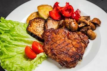 Grilled pork meat with grilled vegetables, mushrooms, tomatos