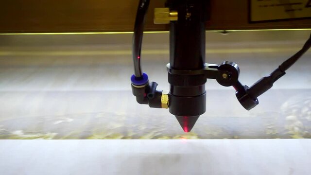 Laser engraving on wood. Laser printer moves on a wooden surface.