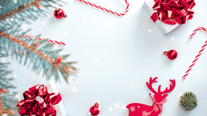 Winter banner. White gifts with scarlet bow, red balls and sparkling lights in xmas decoration on white background for greeting card. Flat lay, top view, copy space.