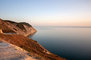 Silhouette of the rocky coast at sunset. Summer sea sunset. Calm at sea in the rays of sunset.