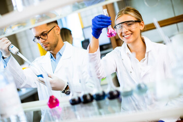 Young female scientist examining liquid in biochemical lab