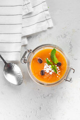 Panna cotta dessert with orange jelly and mint in a glass jar on a kitchen, top view