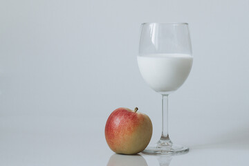 Image of a glass of white drink and red apple on a white background