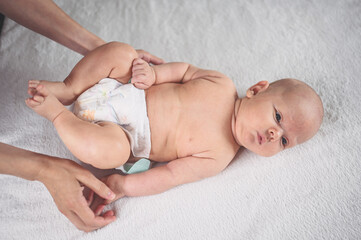 Mother is changing diaper for cute emotional funny newborn little infant baby boy laying in crib